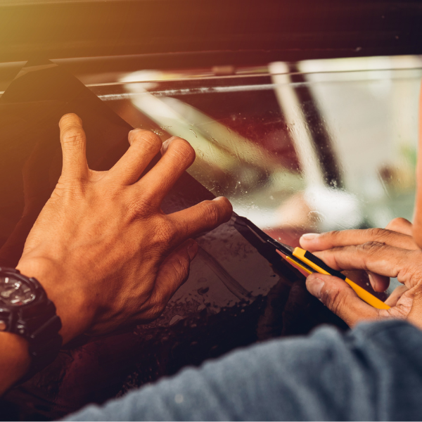 hands working with a blade to install auto window film